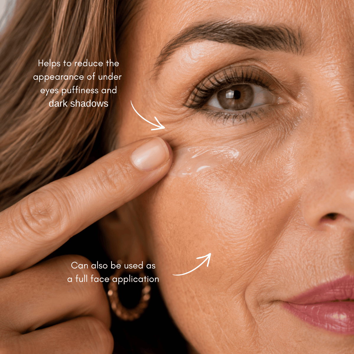 Close-up of a woman's face with white cosmetic cream applied under her eyes, showing text overlays that explain the product benefits: 'Helps to reduce the appearance of under eyes puffiness and dark shadows' and 'Can also be used as a full face application'.